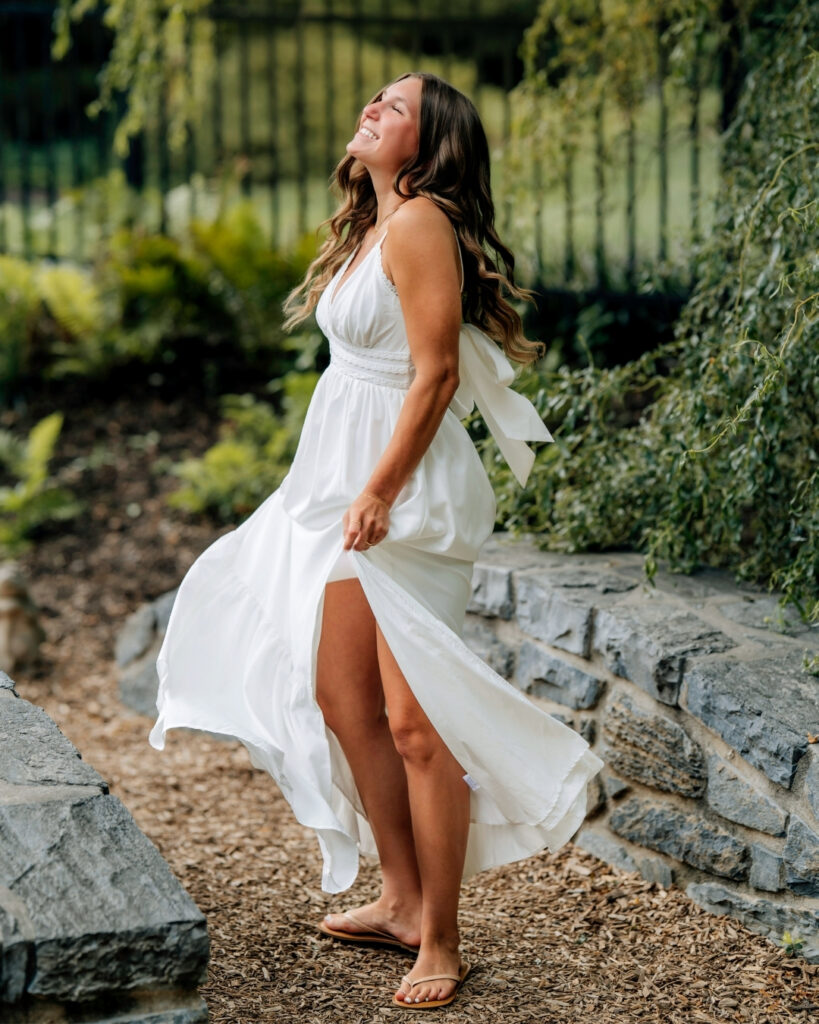 Senior girl laughing in a flowing white dress during outdoor senior pictures in Hershey PA