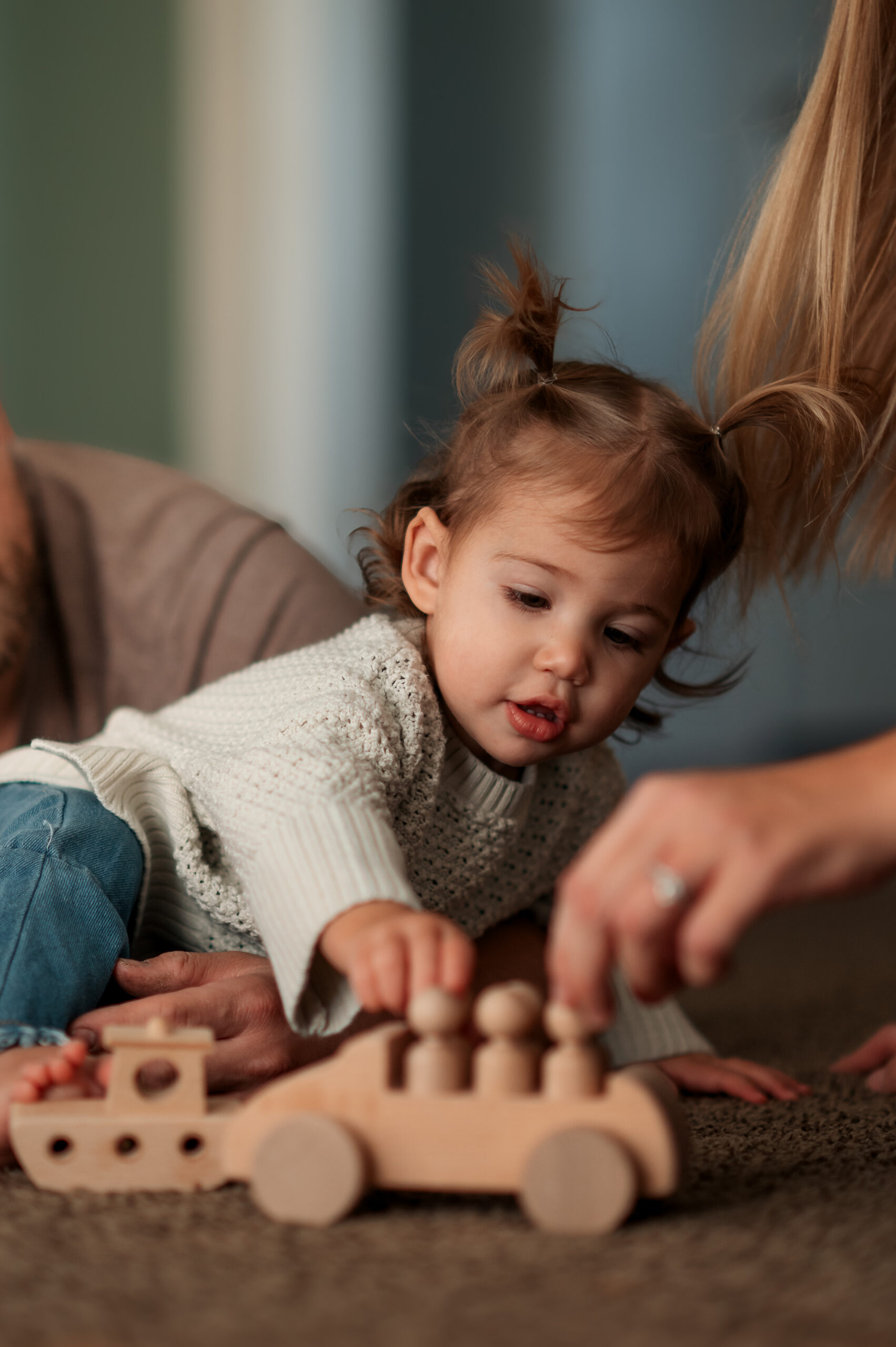 Young girl playing with a wooden toy at home during a documentary family photography session